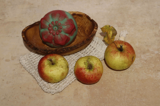 Dies ist ein Foto von eine grün rote Körperseife Blüte Apfel der Firma Eleona und 3 Äpfel auf einem Seifensäckchen