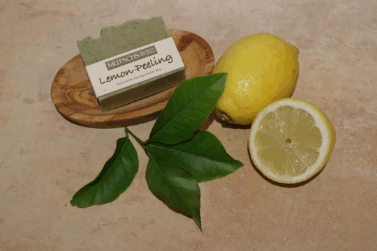 Dies ist ein Foto von einer grünen Körperseife Lemon-Peeling der Firma Mutschs und eine ganze und eine halbe Zirone plus ein Zironenzweig